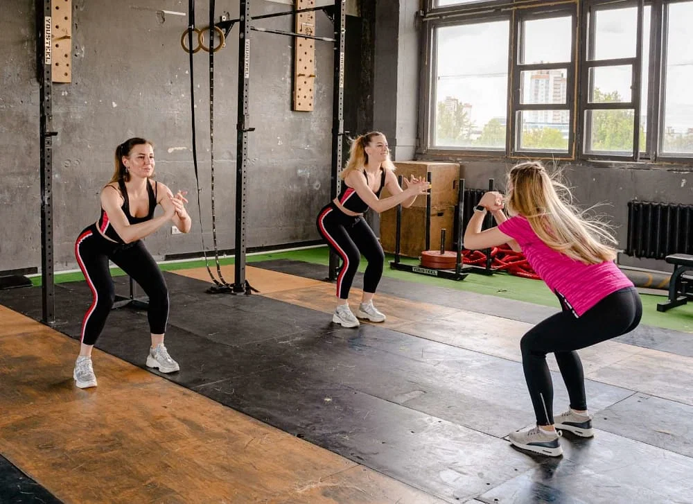 Beautiful girls having long hairs doing squats for losing weight.

